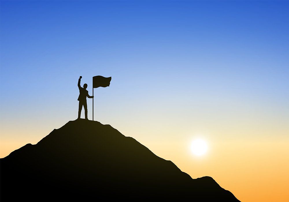 Silhouette of businessman and flag on top mountain, sky and sun light background. Business, success, leadership, achievement and people concept