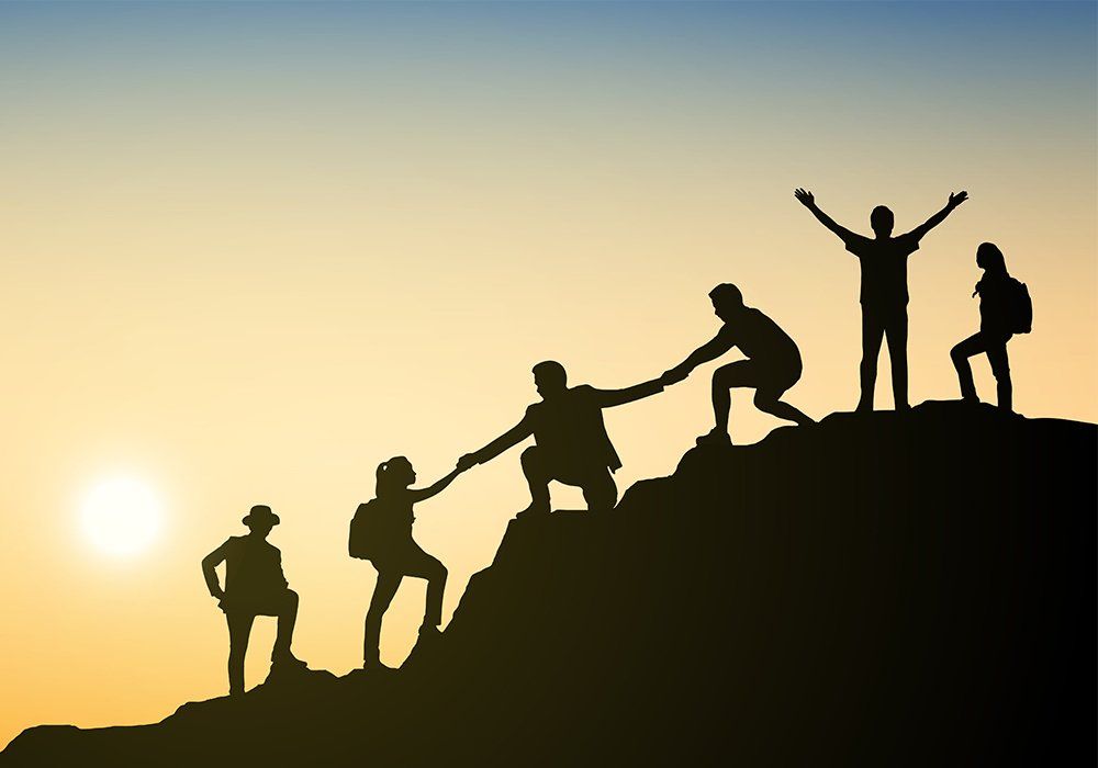 Silhouettes group businessman climbing on mountain and helping at sunset