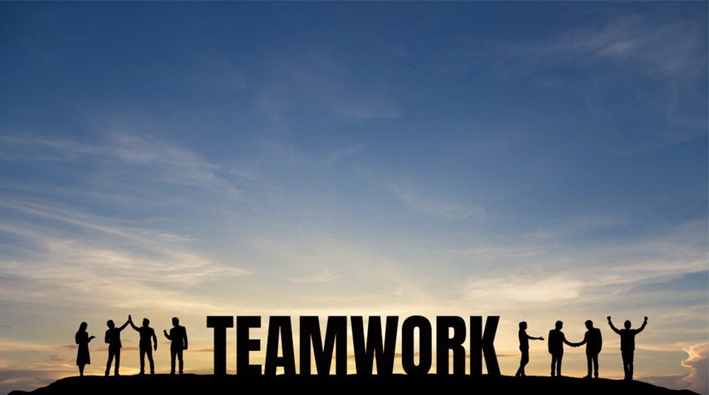 Silhouette group of business man and woman celebrating success, and text TEAMWORK on top mountain, sky and sun light background. Business, successful, leadership, achievement, team and goal concept.