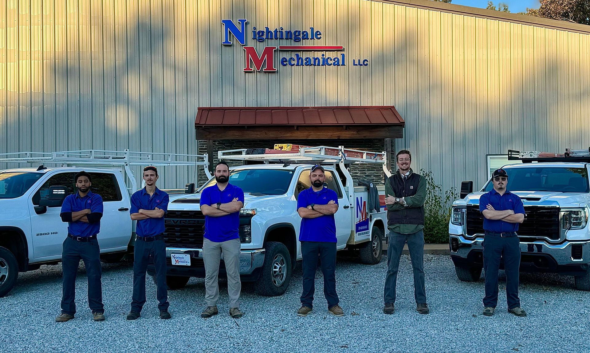 A group of men standing in front of a building with trucks parked in front of them.