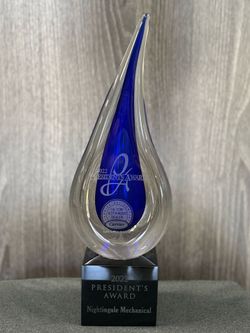 A blue glass trophy is sitting on top of a wooden table.