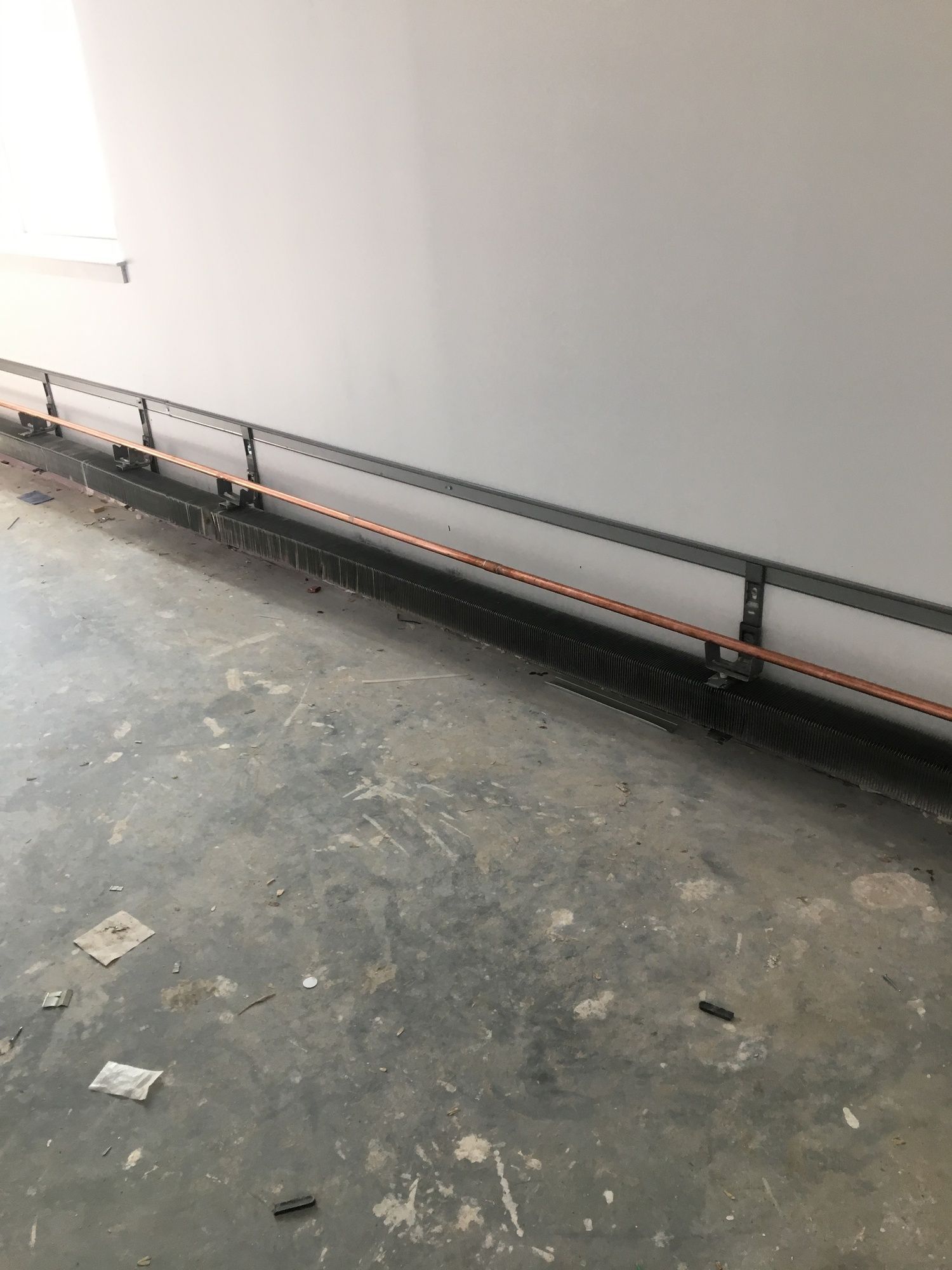 A room with a concrete floor and a metal railing on the wall.