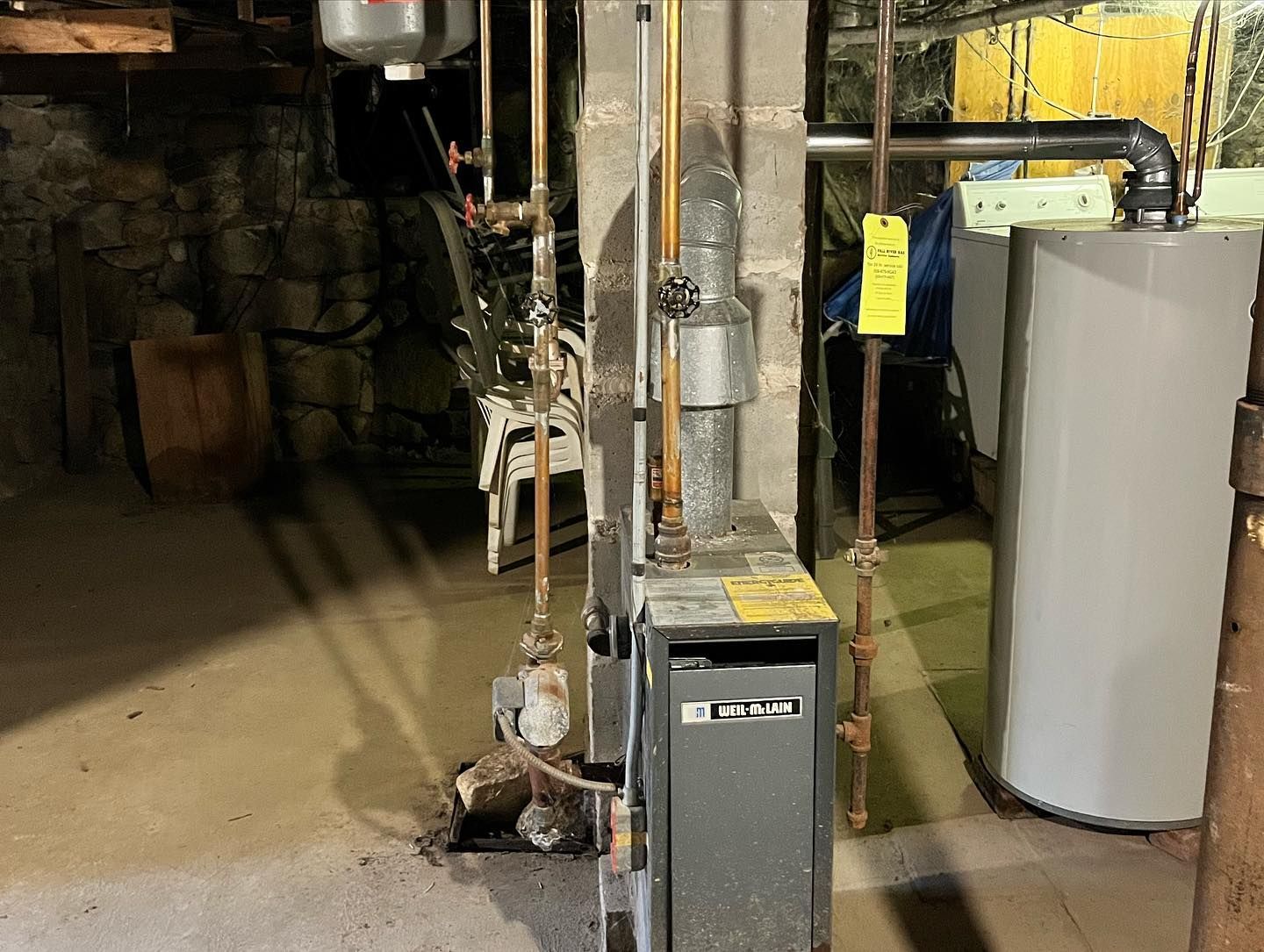 A boiler and a water heater are in a basement.