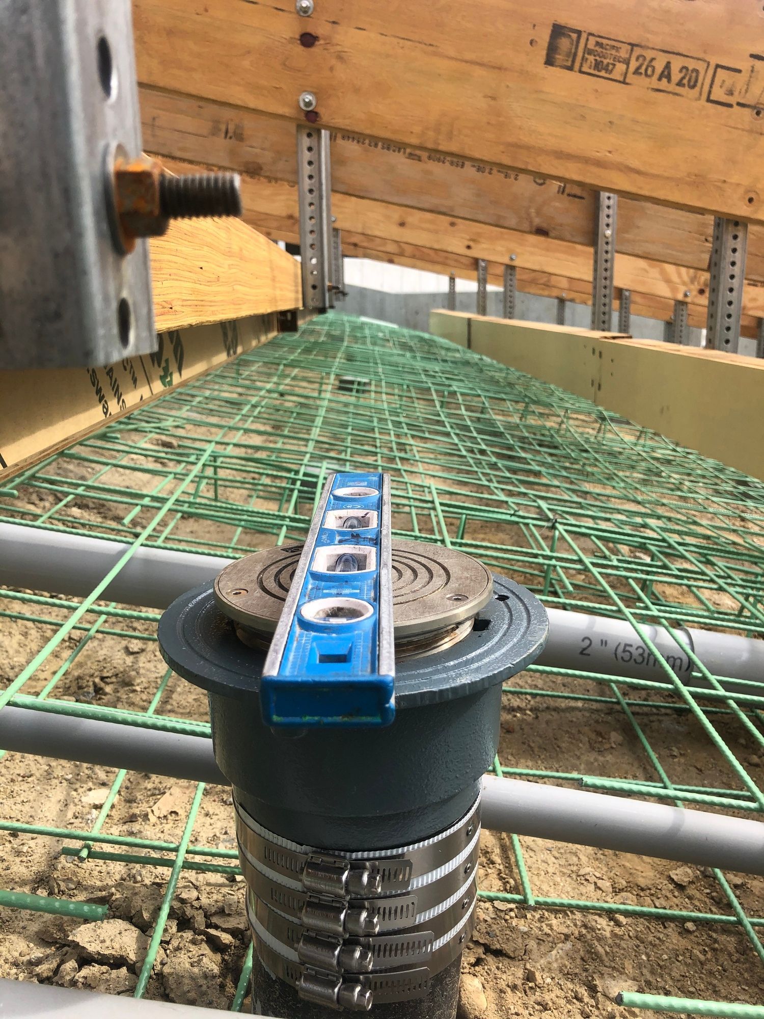 A blue level is sitting on top of a drain on a construction site.