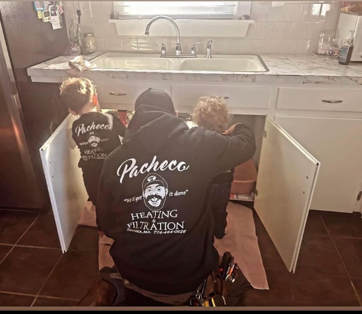 A plumber is working under a sink in a kitchen