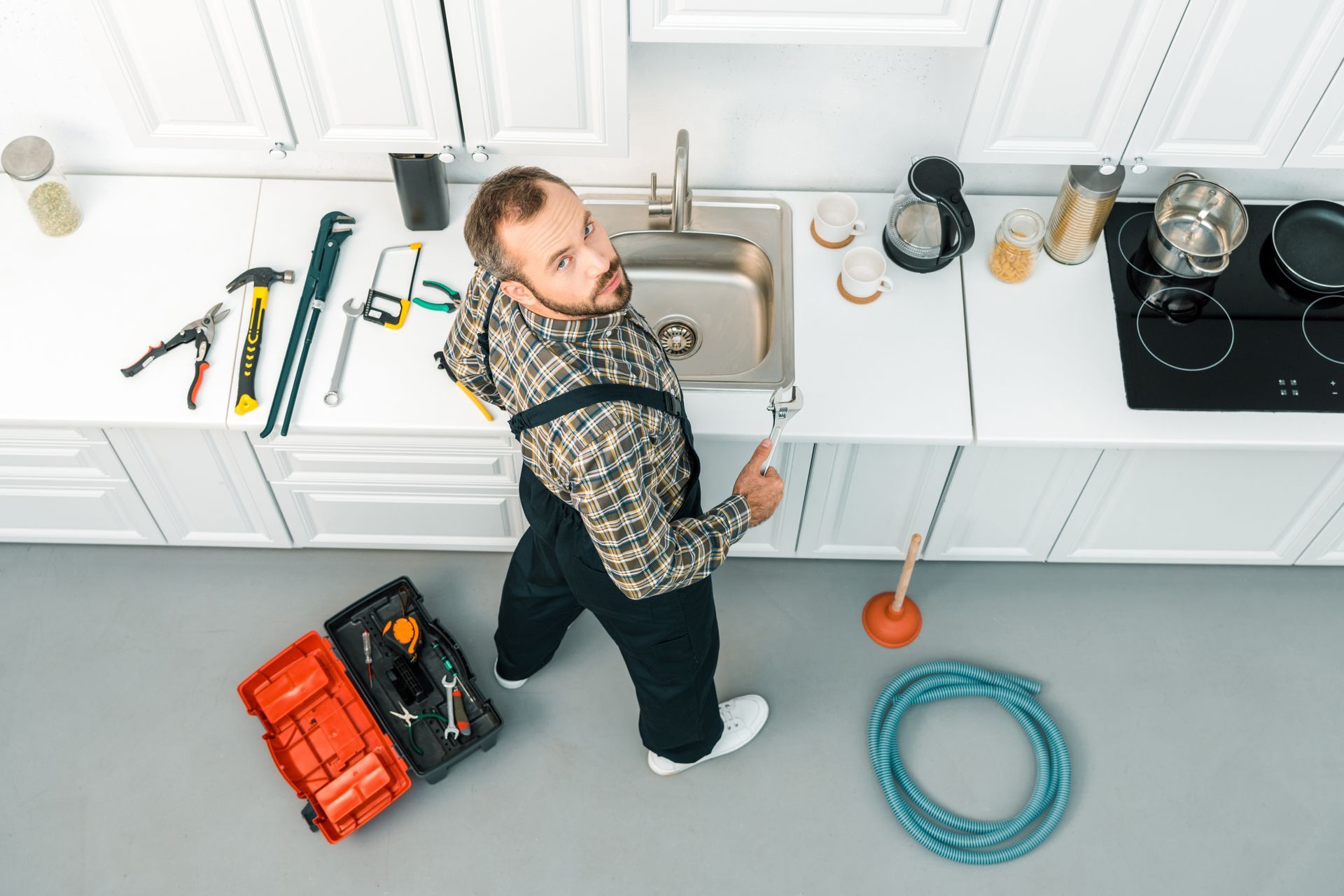 A plumber is fixing a sink in a kitchen.