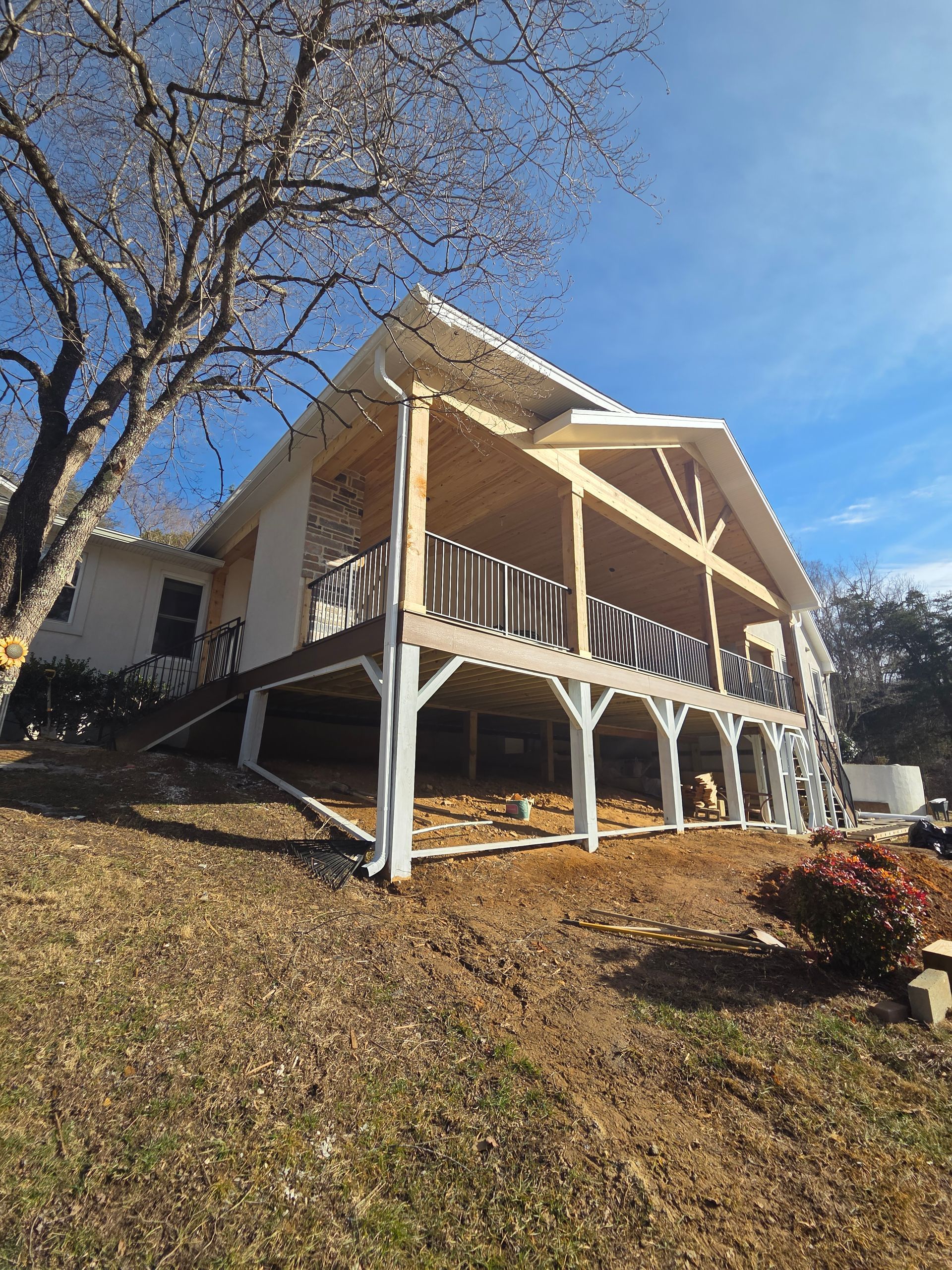 Wicker chair with yellow cushion on a tiled patio, next to a table with lemon-print tablecloth and a slatted wall.
