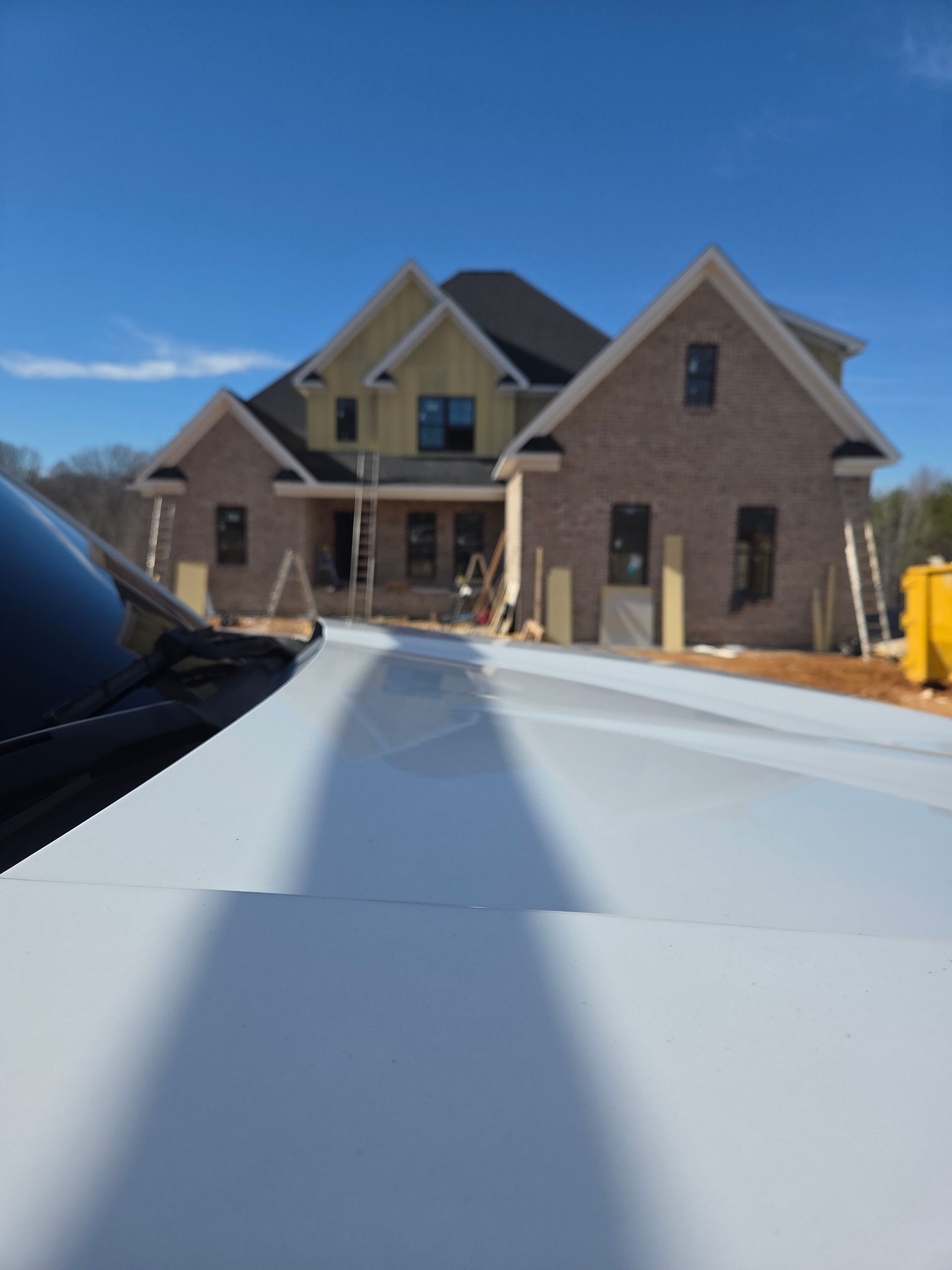 White building with four windows, each covered by a closed, white rolling shutter.