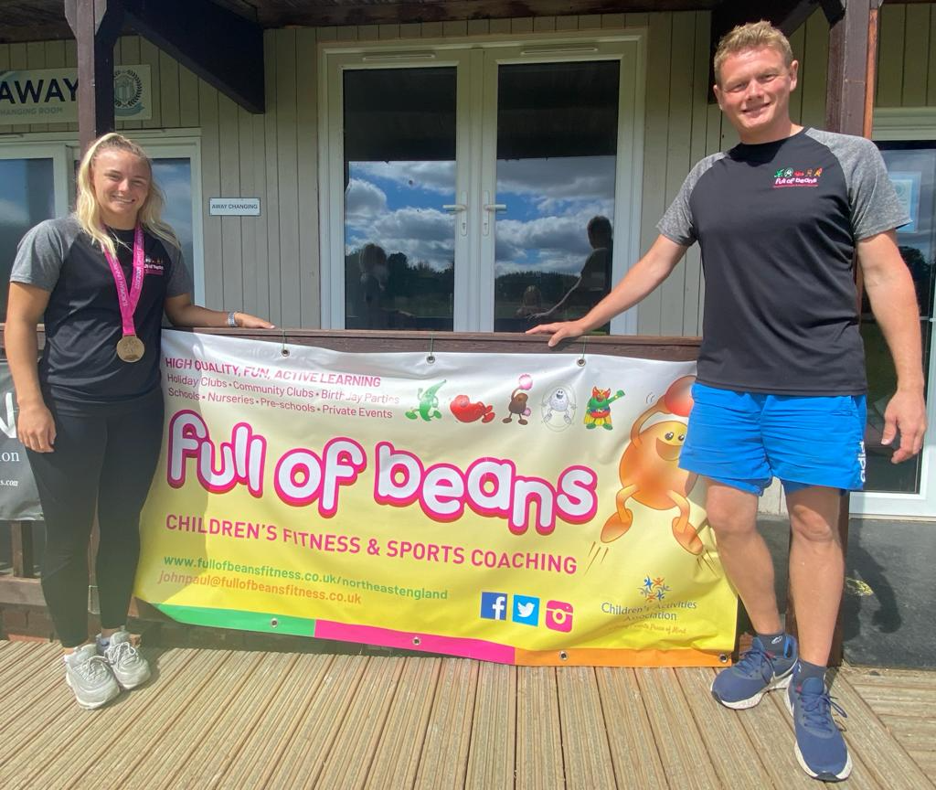 A man and a woman are standing in front of a full of beans sign.