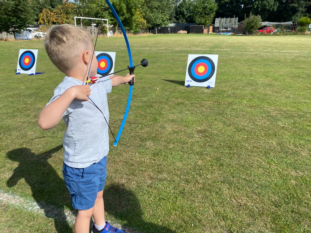 A young boy is practicing archery in a field.
