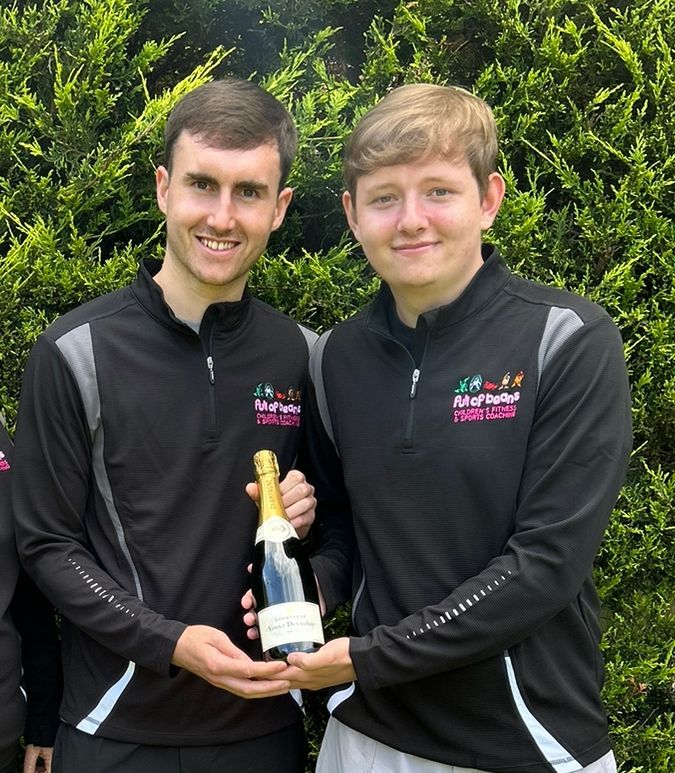 Two young men are holding a bottle of champagne in their hands.