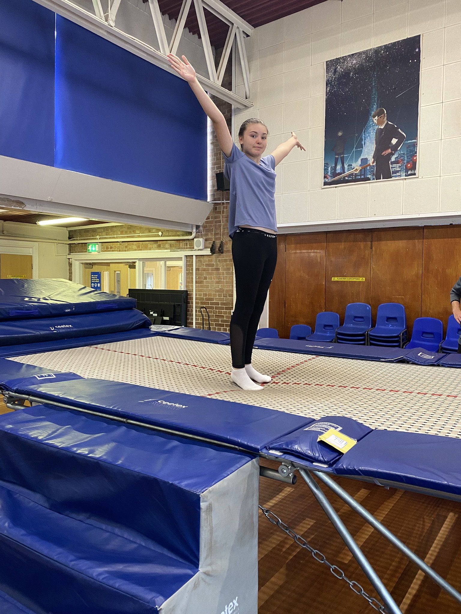 A young girl is jumping on a trampoline in a gym.