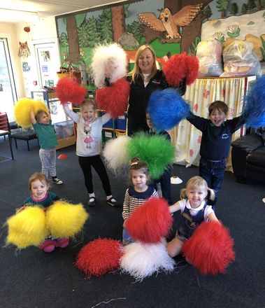 A group of children holding up pom poms in a room