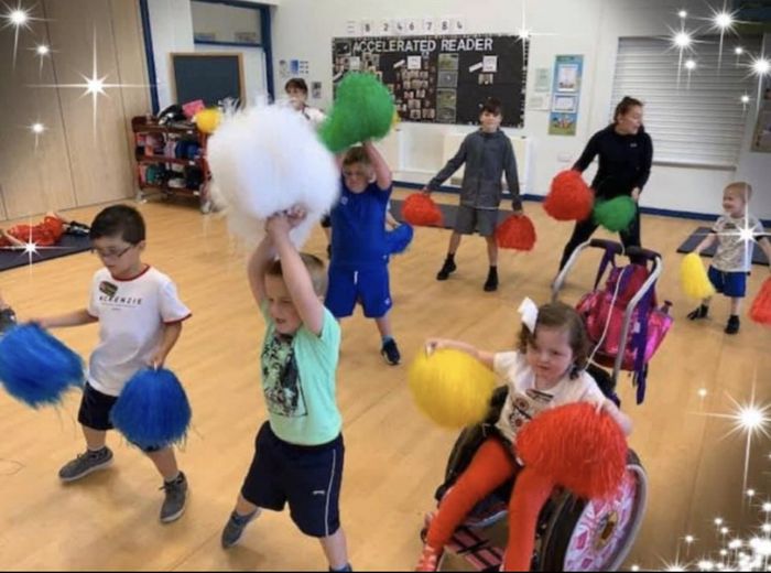 A group of children are playing with pom poms in a gym