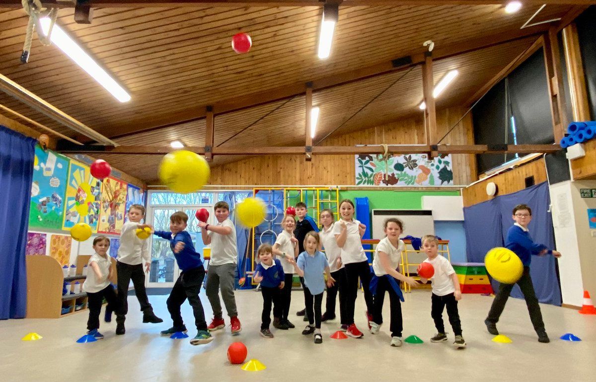 A group of children are playing with balls in a gym.