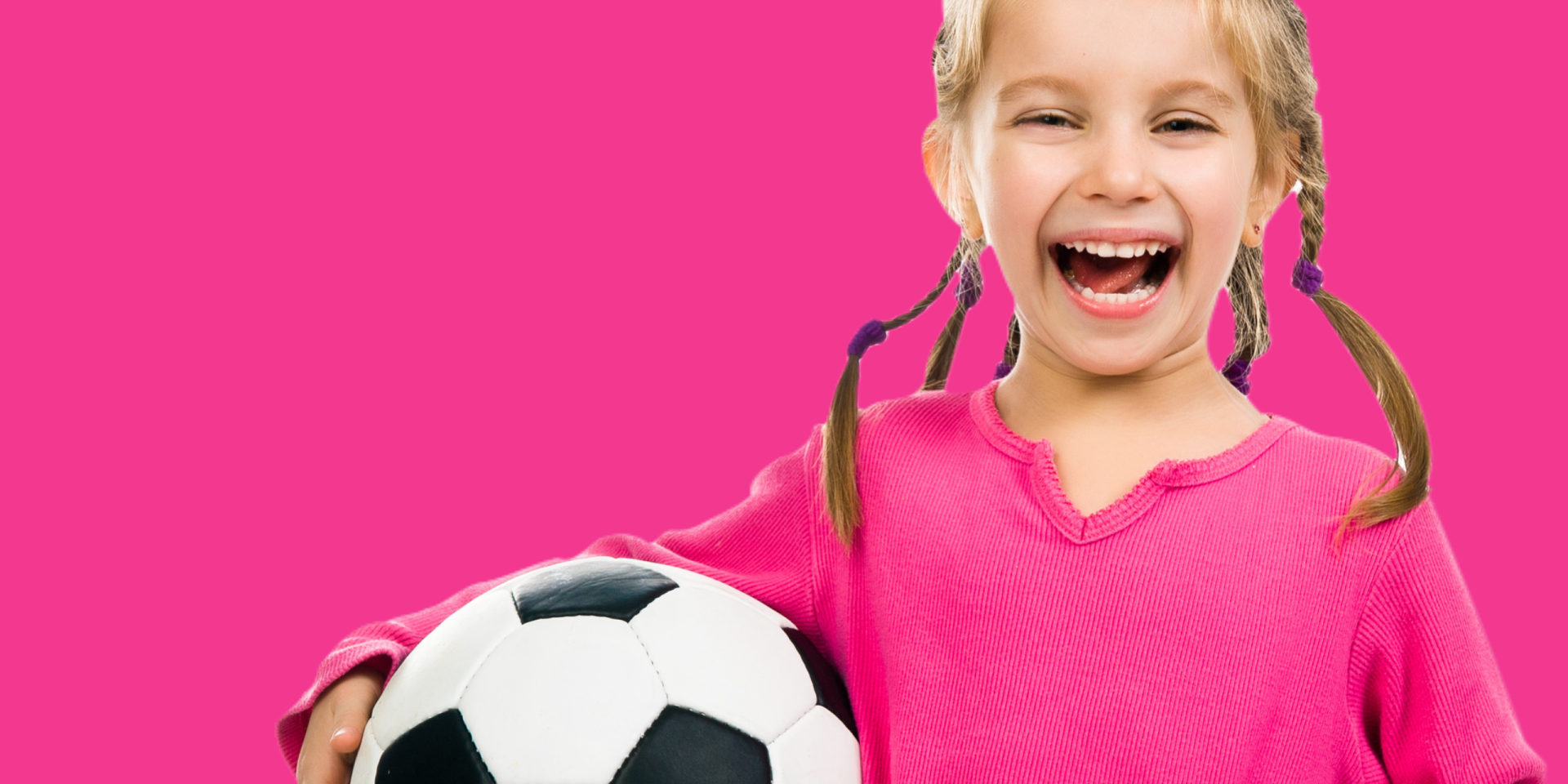 A little girl is holding a soccer ball on a pink background.