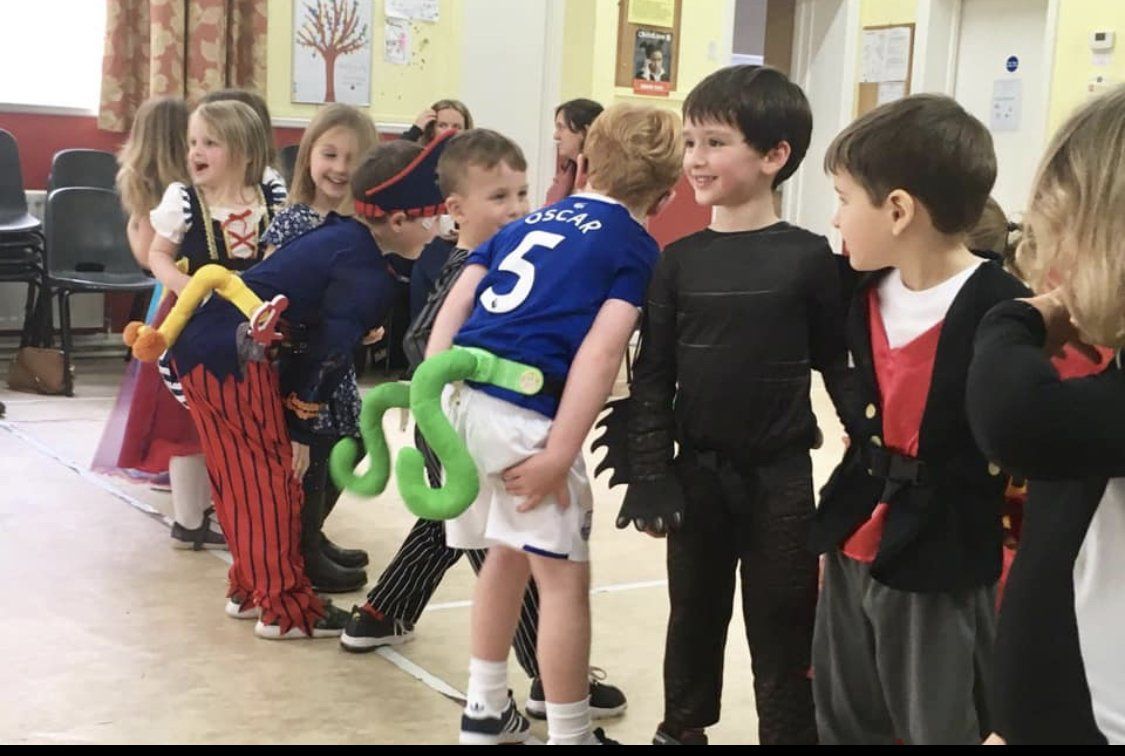 A group of children dressed in costumes are standing next to each other in a room.