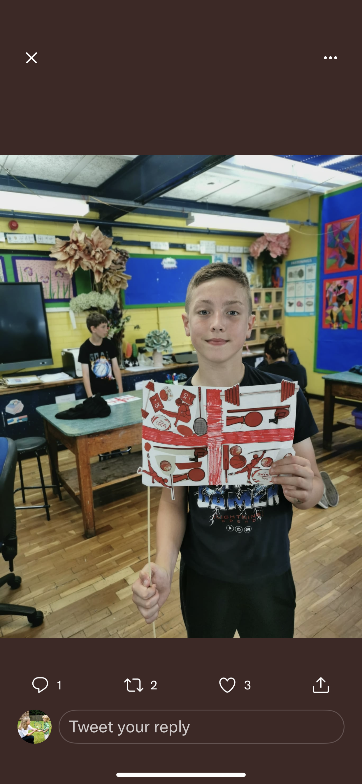 A young boy is holding a british flag in a classroom.