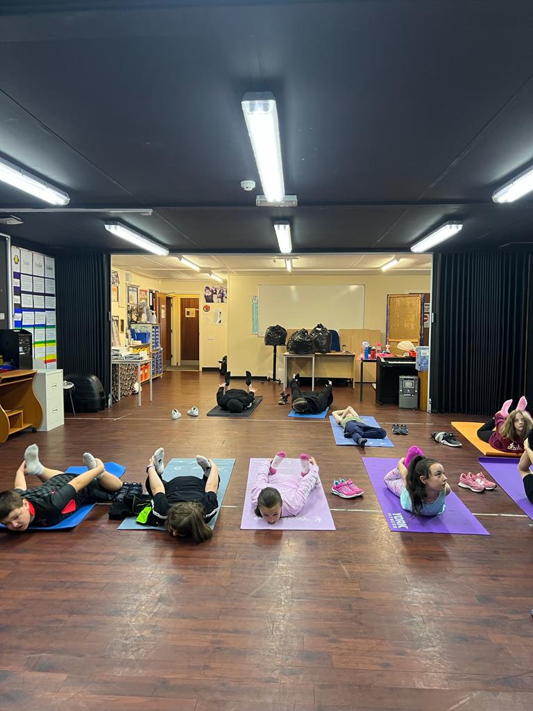 A group of children are laying on yoga mats in a room.