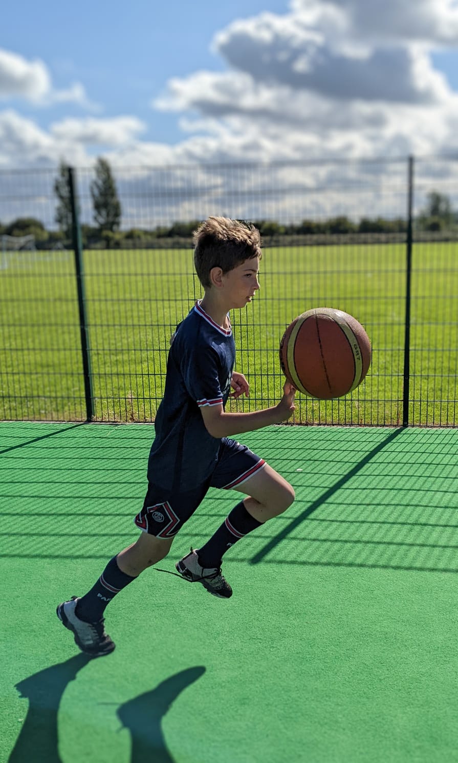A young boy is dribbling a basketball on a green court.
