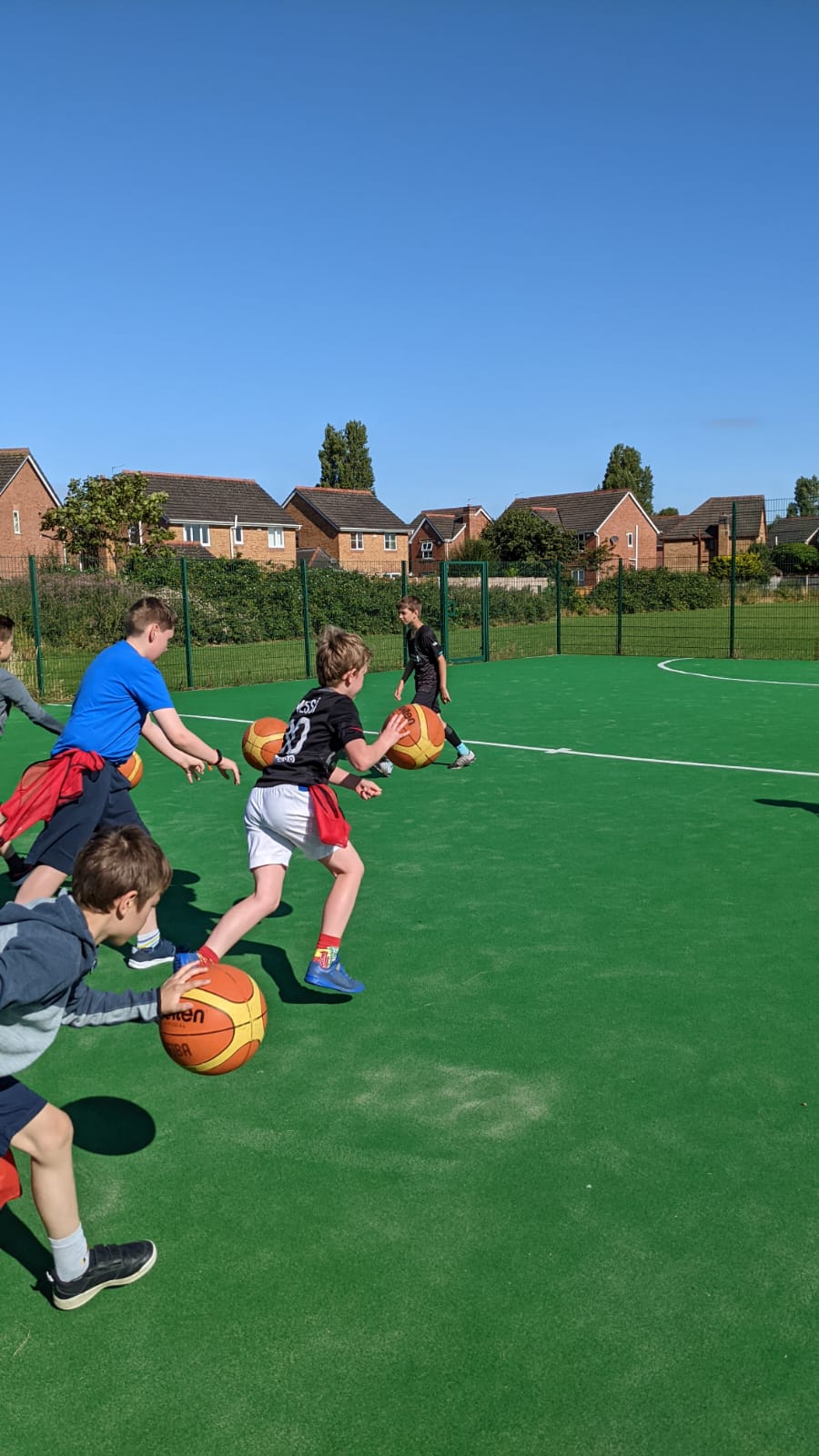 A group of children are playing soccer on a green field.