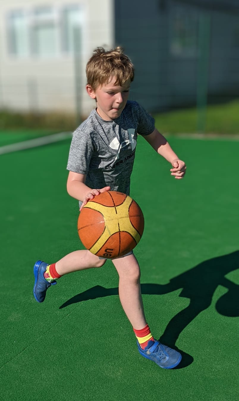 A young boy is running with a basketball on a field.