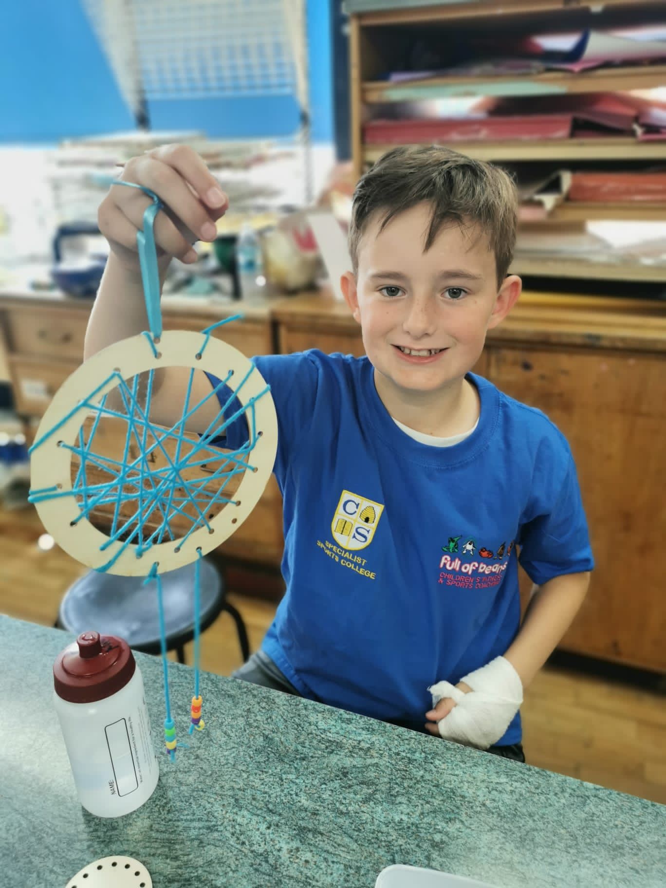 A young boy in a blue shirt is holding a dream catcher