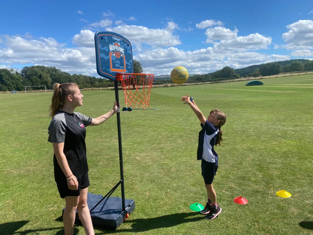 A woman and a child are playing basketball in a field.