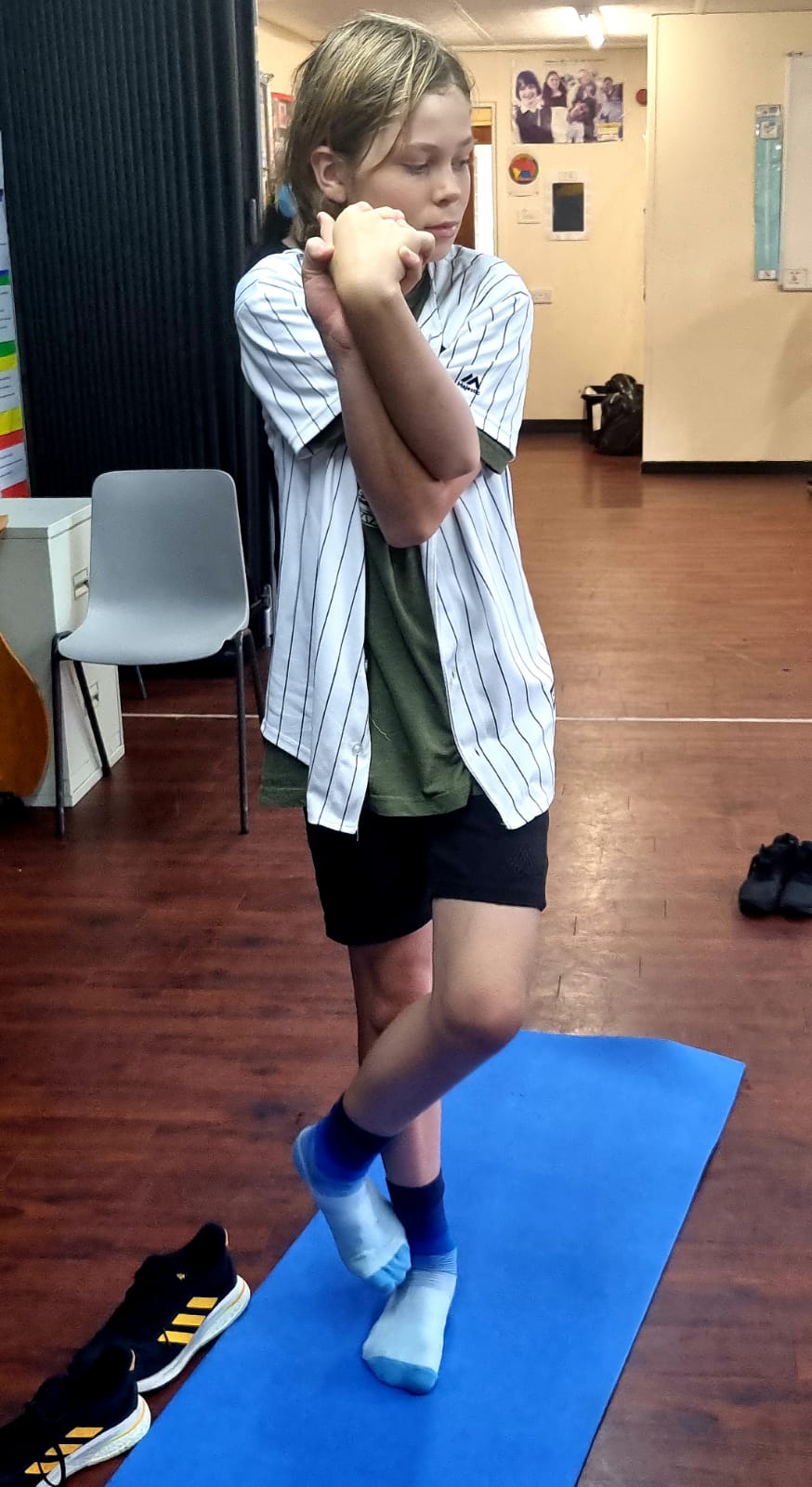 A young girl is standing on a blue yoga mat.