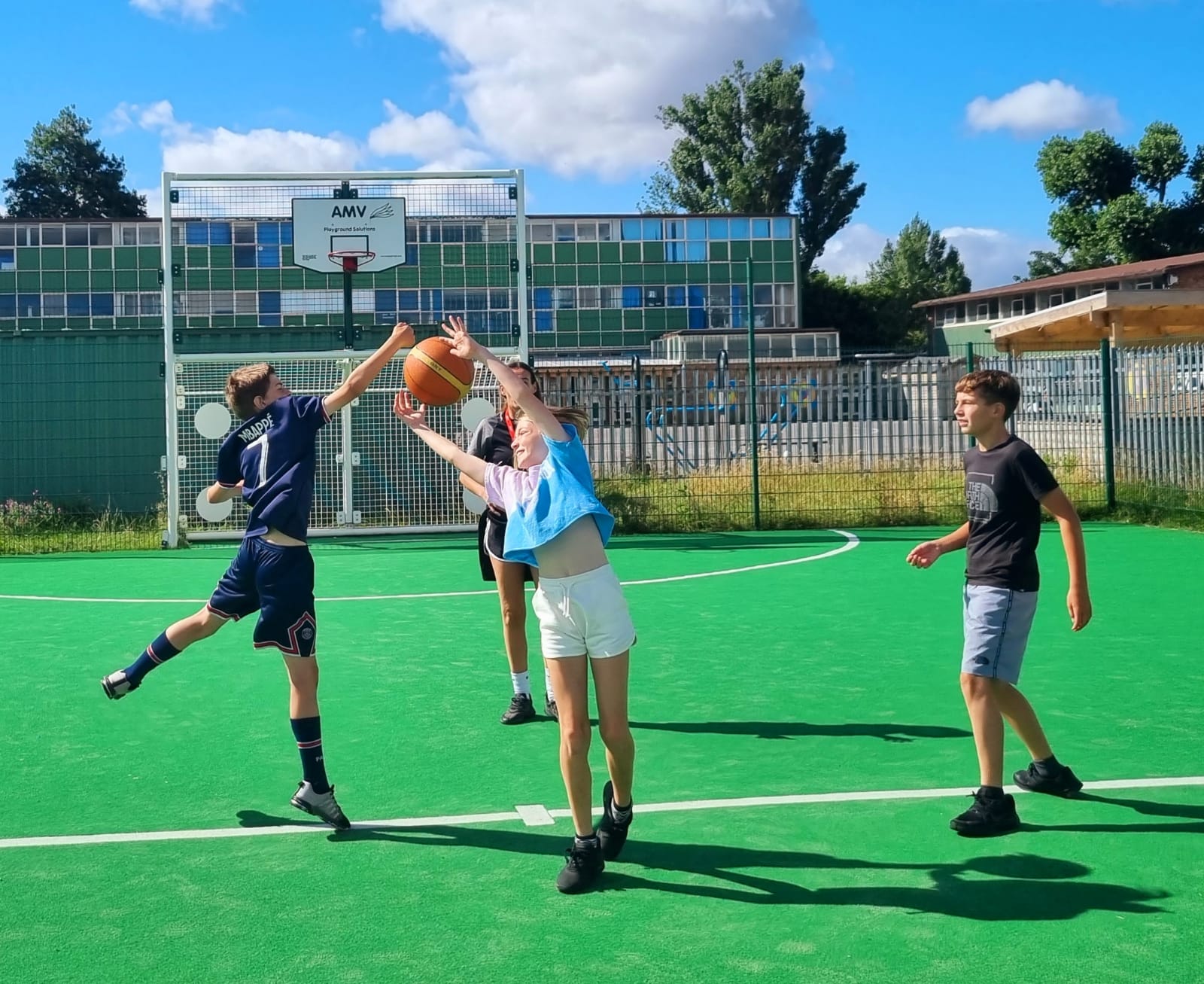 A group of children are playing basketball on a green field.