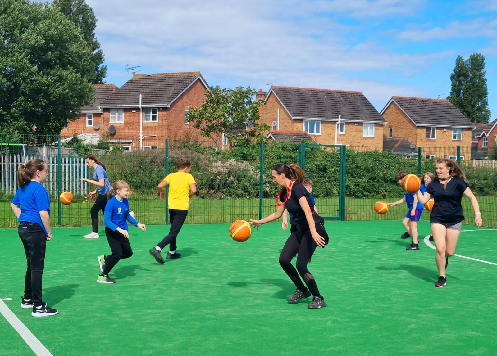 A group of children are playing basketball on a green field.