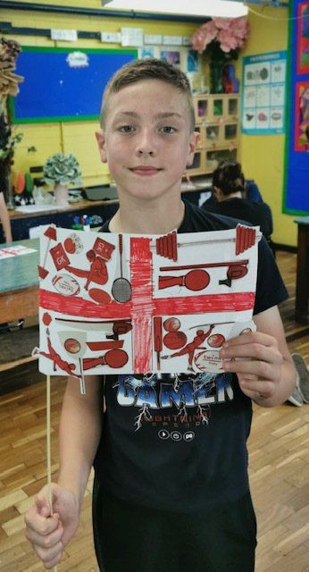 A young boy in a black shirt is holding a cardboard british flag