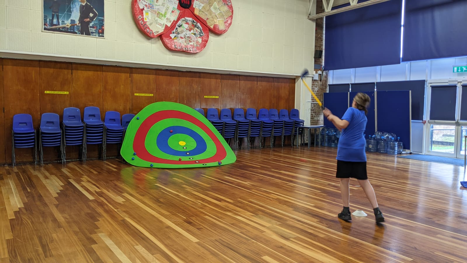A man in a blue shirt is throwing a frisbee in a room.