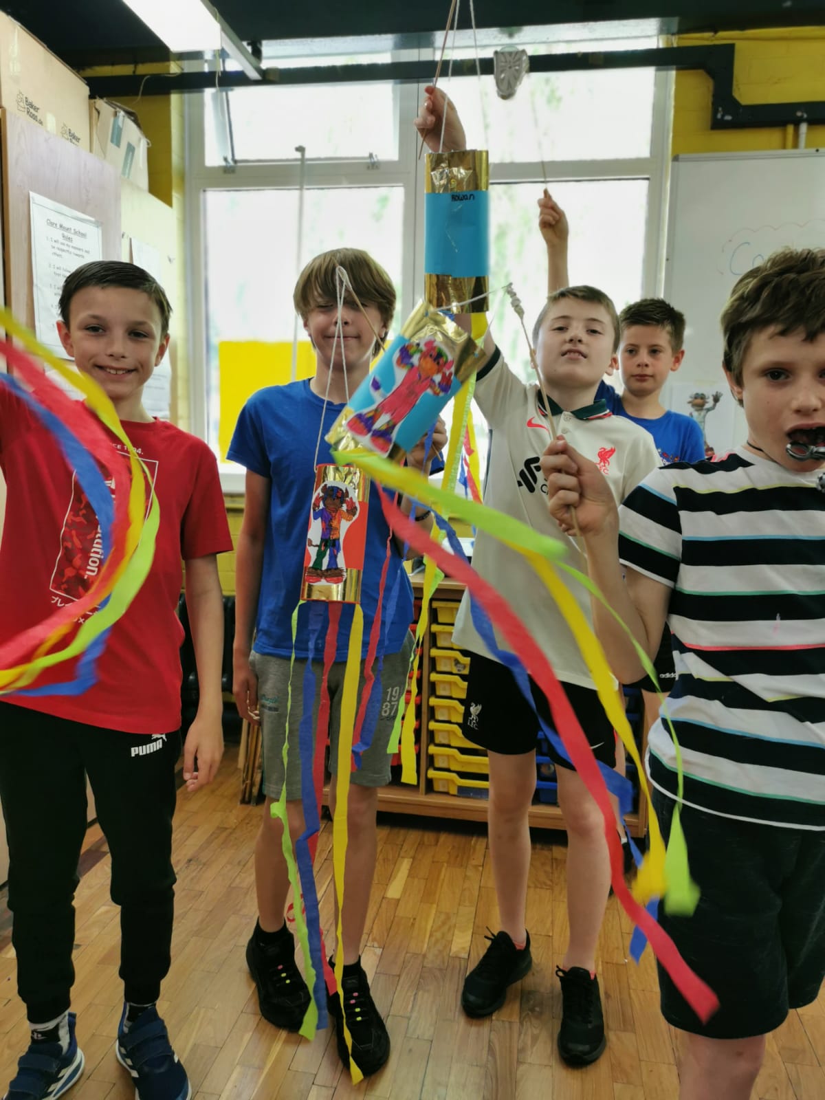 A group of young boys are standing in a room holding colorful ribbons.