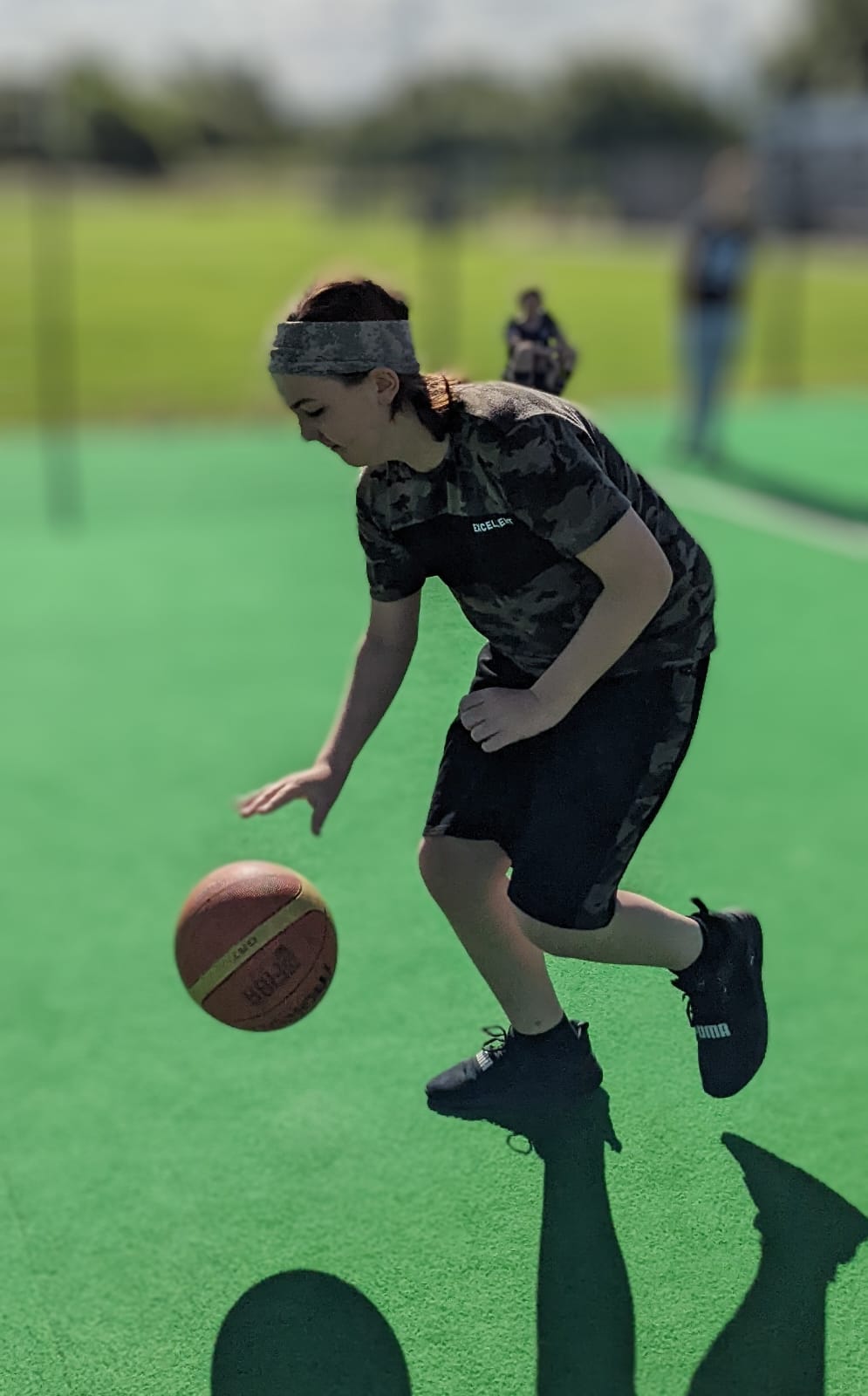 A person is dribbling a basketball on a field.