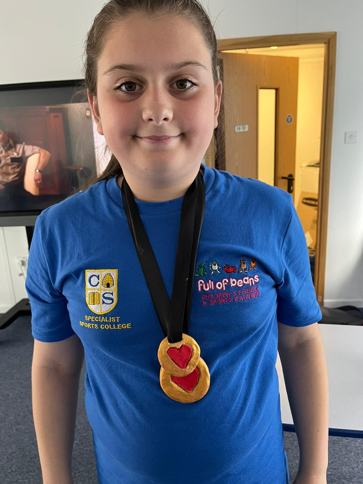 A young girl wearing a blue shirt and a medal around her neck.