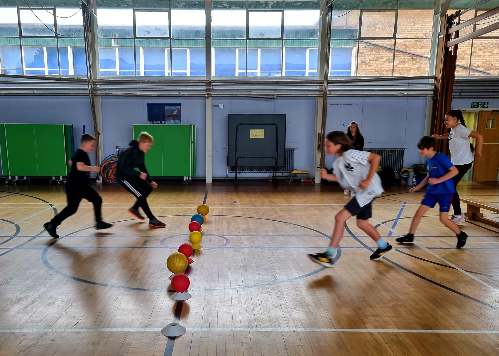 A group of children are playing a game of dodgeball in a gym