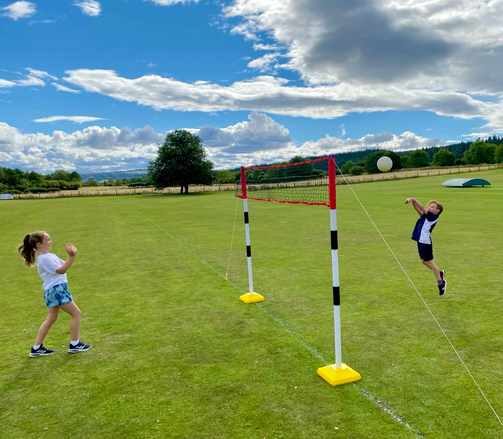 A boy and a girl are playing volleyball in a field.