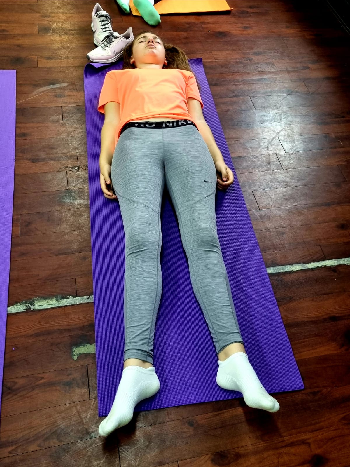 A woman is laying on a purple yoga mat.