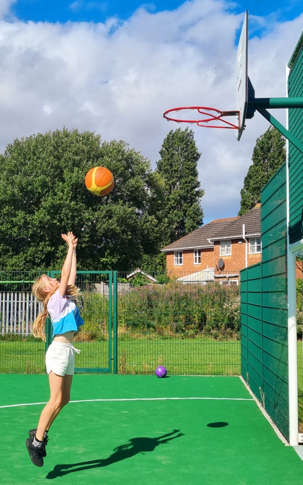 A young girl is playing basketball on a court.