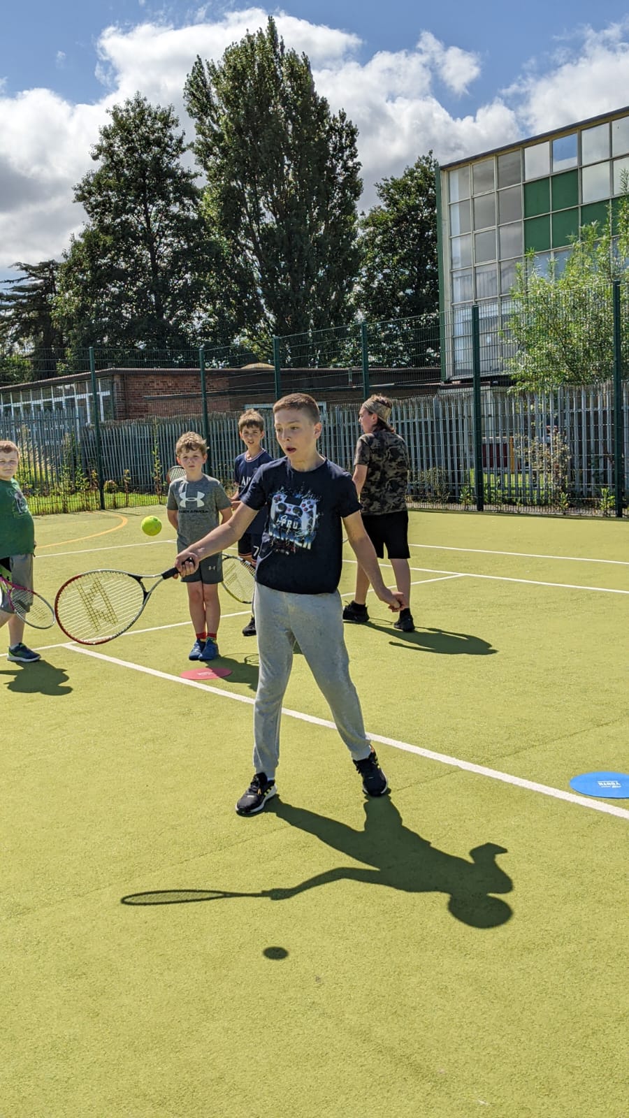 A group of children are playing tennis on a court.