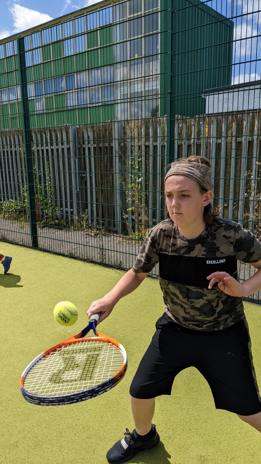 A young boy is playing tennis on a court.