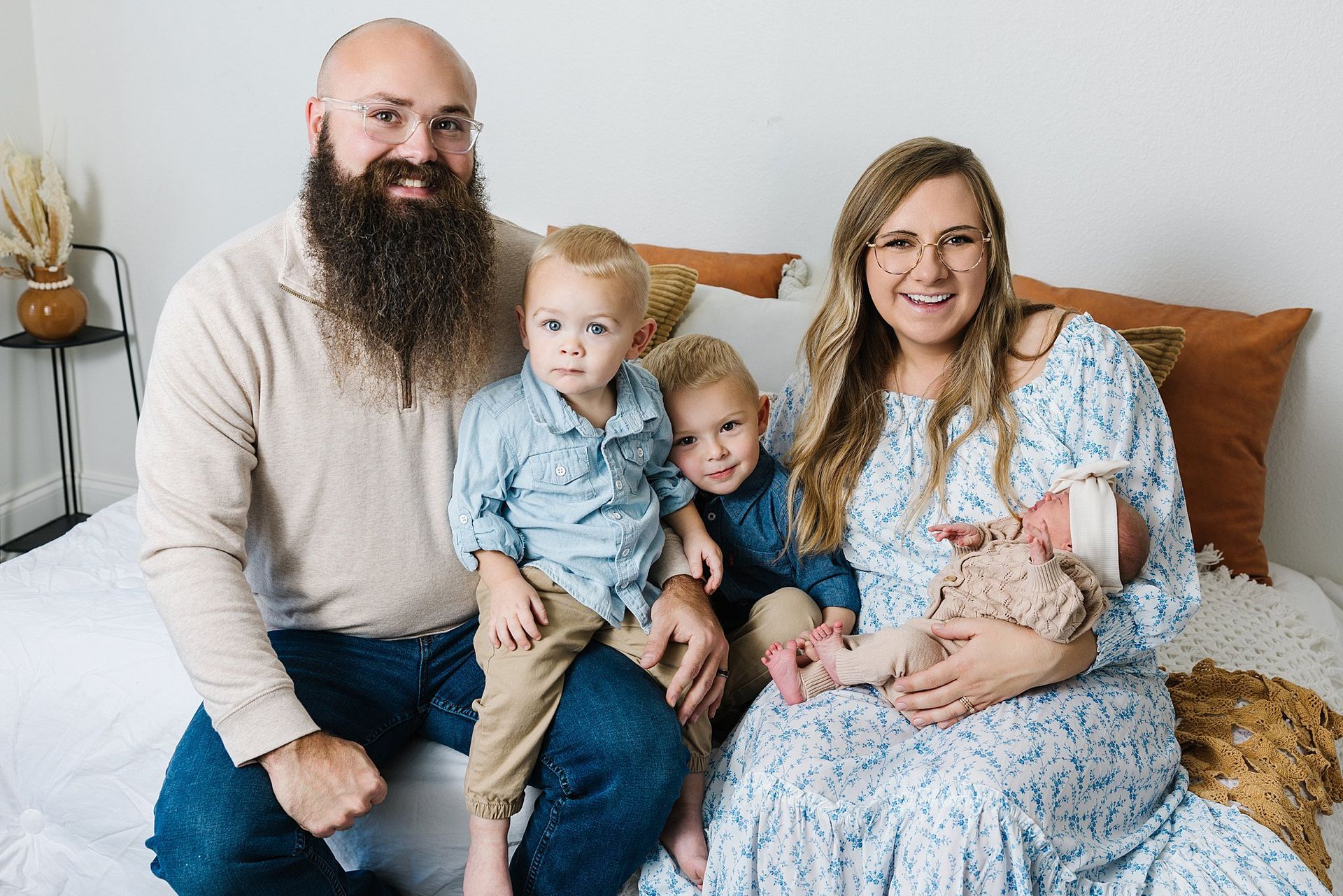 Playful unposed family of five cuddling newborn on all white studio‑room couch lifestyle session Burrton KS Sara McMillian