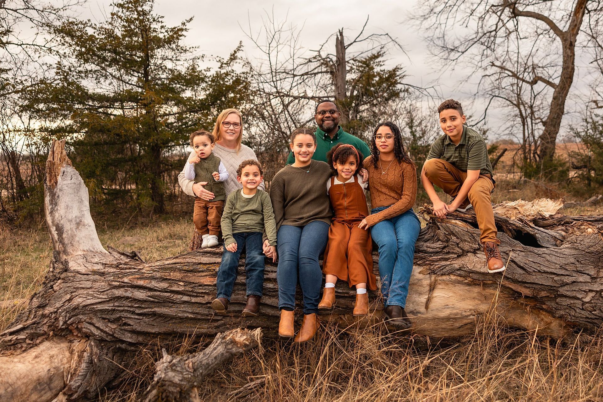 Playful unposed family laughing beside fallen tree trunk during farm mini session Burrton KS Sara McMillian Photography