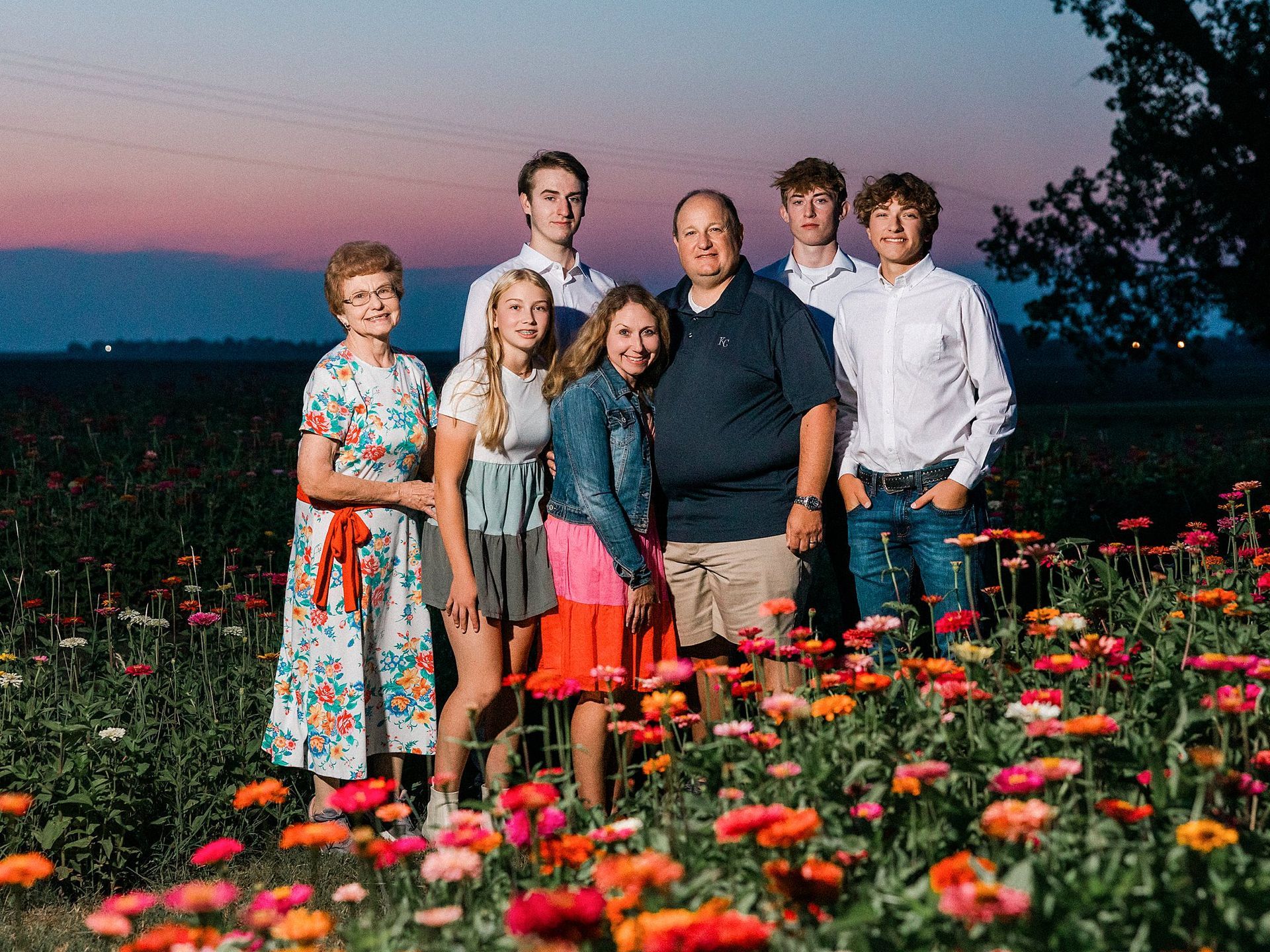 Family posing in a field of colorful flowers, at dusk.