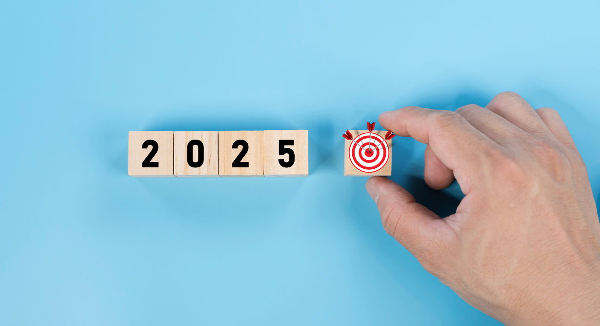 Hand placing a target icon next to “2025” blocks on a blue background