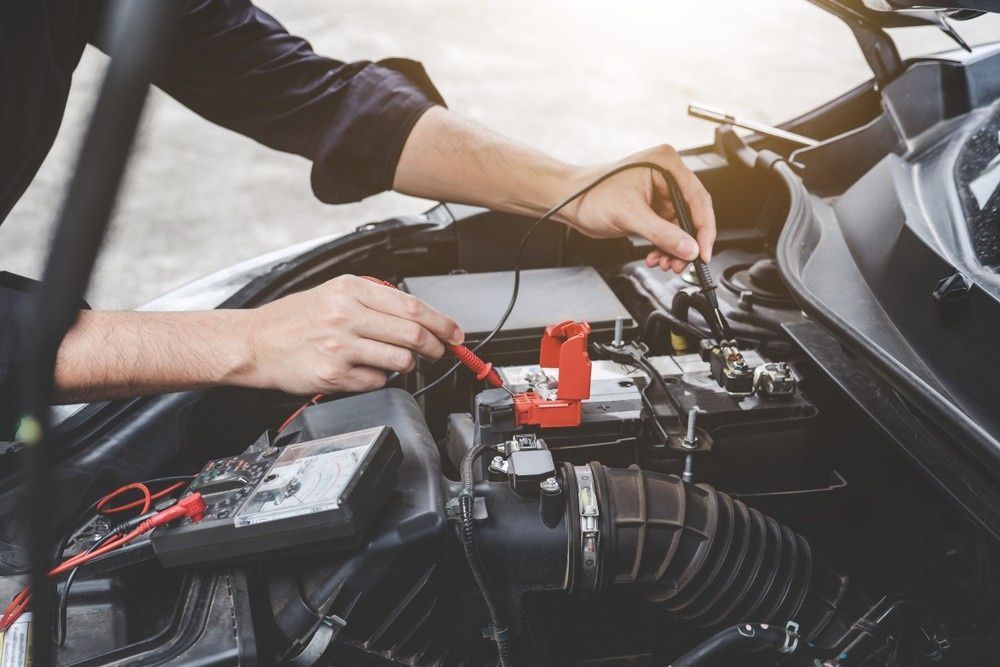 A Mechanic Using a Multimeter to Test a Car Battery — Woden Automotive Services in Phillip, ACT