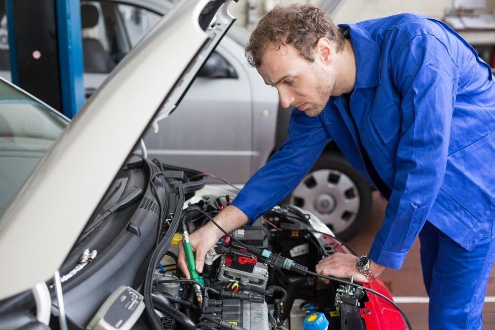 A Mechanic Working on A Car Engine in A Garage — Woden Automotive Services in Phillip, ACT