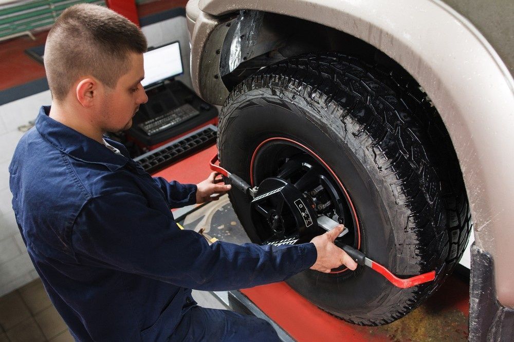 A Mechanic Aligning a Car Tire in A Garage — Woden Automotive Services in Woden, ACT