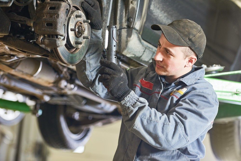 A Mechanic Inspecting Car Brakes — Woden Automotive Services in Mawson, ACT